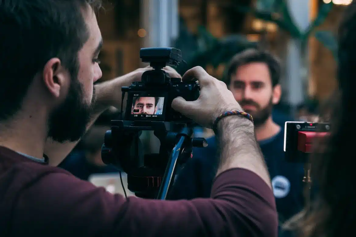 man taking video of standing man wearing black crew-neck top